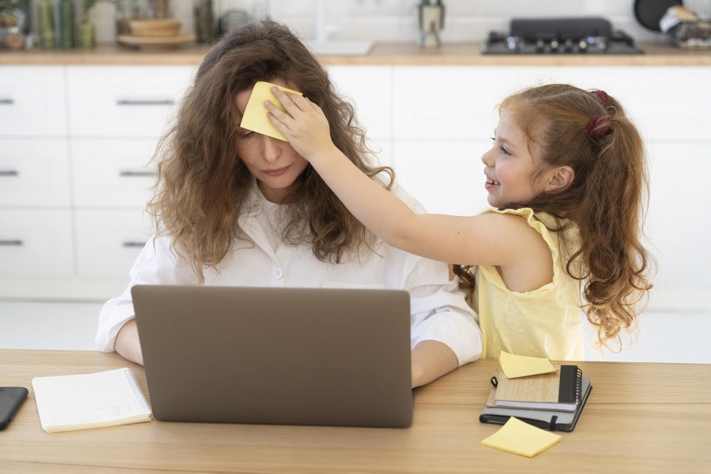 A mum trying to work on her laptop while her daughter tries to distract her.